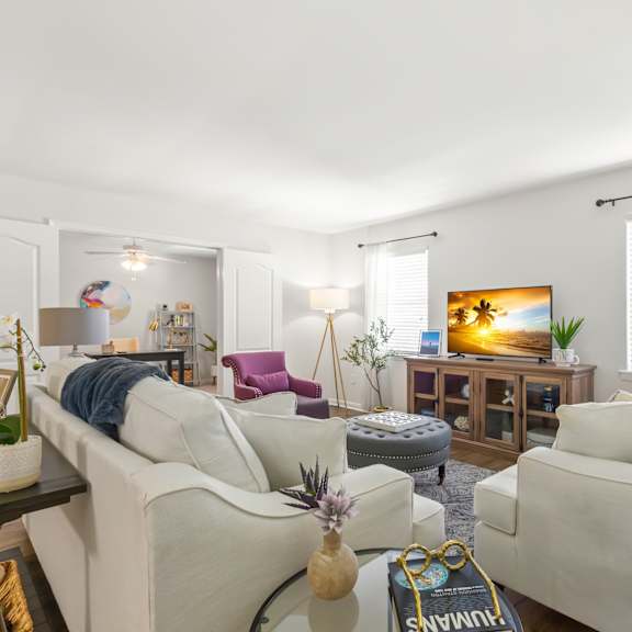 a living room with white furniture and a painting on the wall.