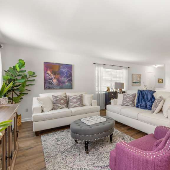 a living room with a pink chair and a grey ottoman.