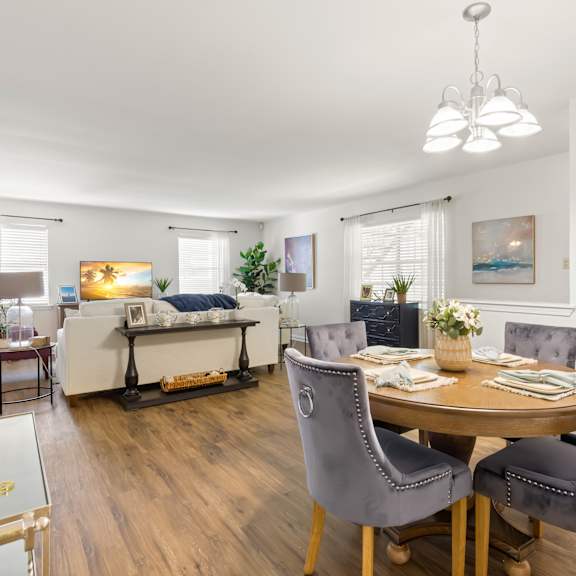 a well-lit, modern dining room with a round table and grey chairs.