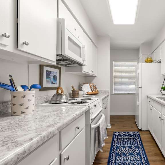 a kitchen with white cabinets and a marble countertop.