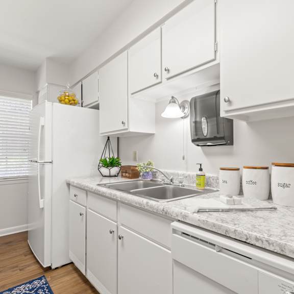 a kitchen with white cabinets and a marble countertop.