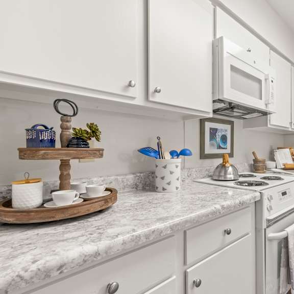 a kitchen with white cabinets and a marble countertop.