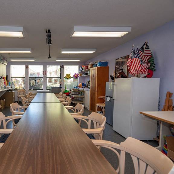 a classroom with a long table and chairs and a window at hilltop commons senior living, california, 95945