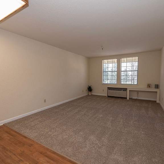 a spacious living room with hardwood floors and a window at hilltop commons senior living, grass valley, 95945