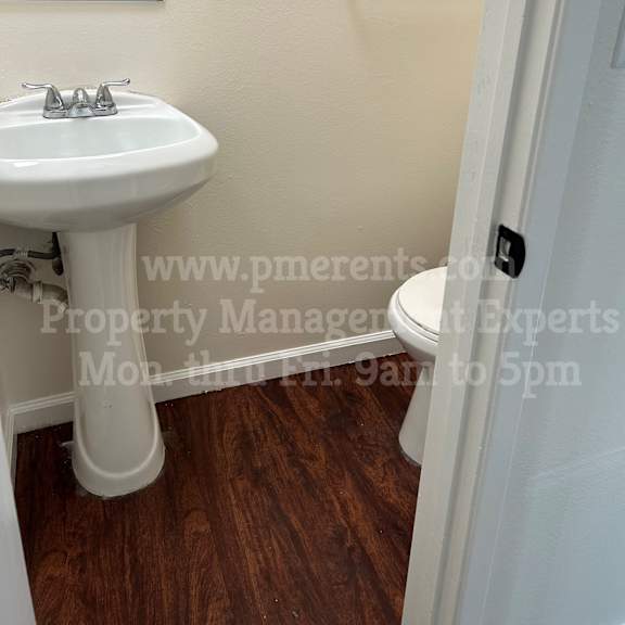 a white sink is in a small bathroom with wood floors.