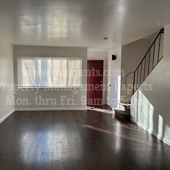 a spacious room with wooden floors and a staircase.