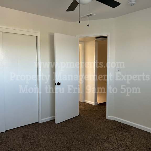 a room with a ceiling fan and a door leading to another room.
