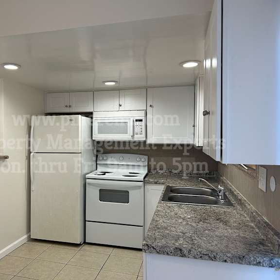 a kitchen with white appliances and a granite countertop.