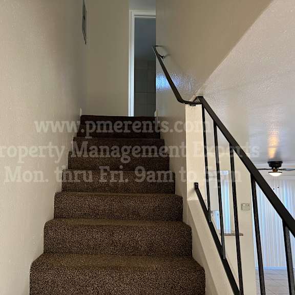 a staircase with a carpeted runner and a metal railing.
