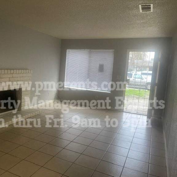 an empty living room with a fireplace and a window