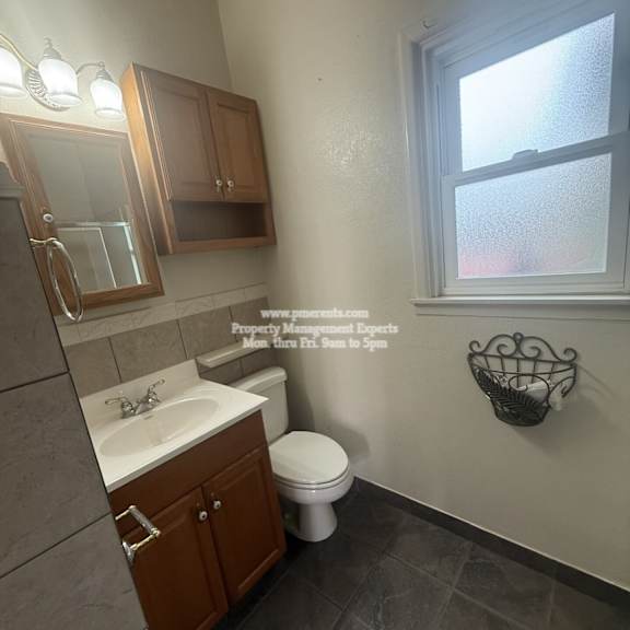 a bathroom with a toilet, sink, and mirror.