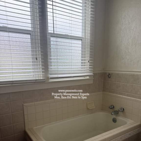 a white bathtub with a tile wall and floor.