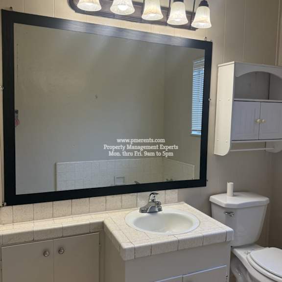 a bathroom with a sink, toilet, and a mirror with a reflection of a website.