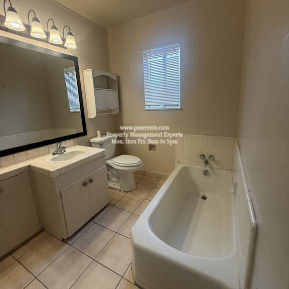 a white bathroom with a tub, sink, and toilet.