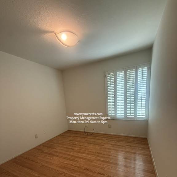 a room with wooden flooring and a window with blinds.
