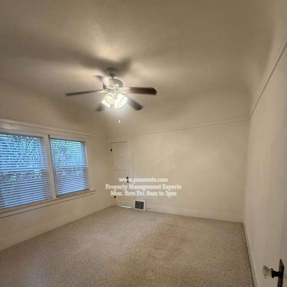 a room with a ceiling fan and carpeted floor.