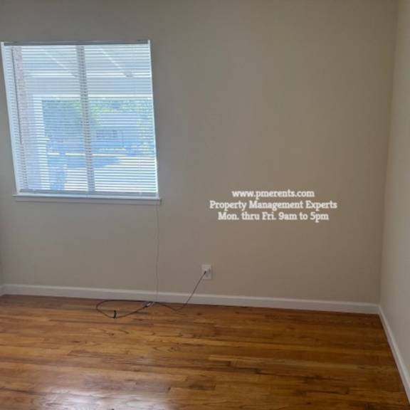 a room with a wooden floor and a window with blinds.