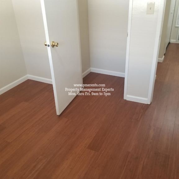 a hallway with a wooden floor and a door on the left.