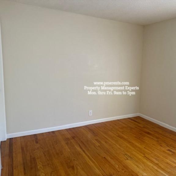 a room with wooden floors and a wall with a website address written on it.