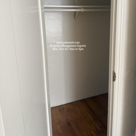 a white closet with a hanger bar and a door.