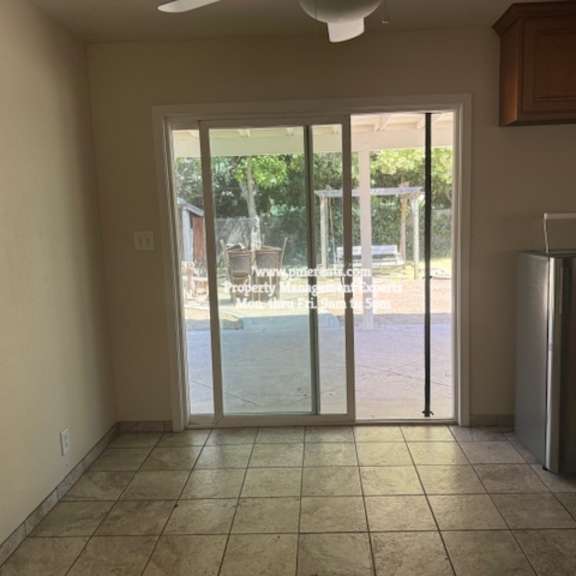 a kitchen with a refrigerator and a sliding glass door leading to a backyard.
