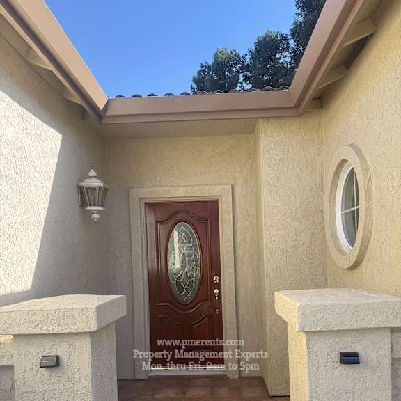 a house entrance with a brown door and a window above it.