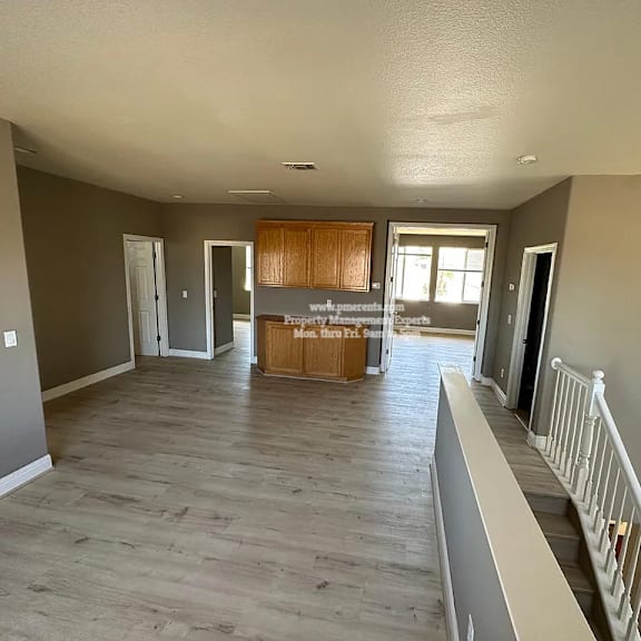 a spacious living room with a kitchen in the background.