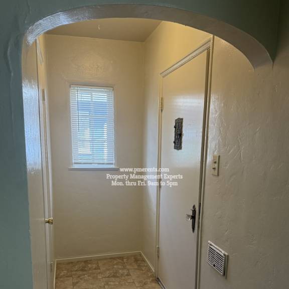 a hallway with a door on the right and a window on the left.