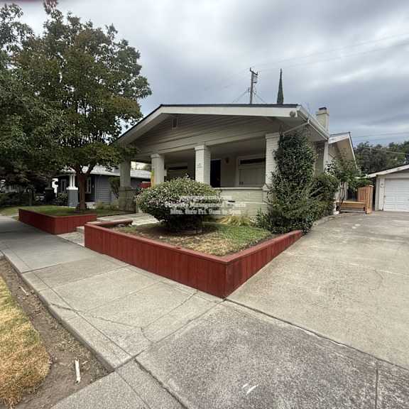 a house with a grey roof and a red border around the front yard.