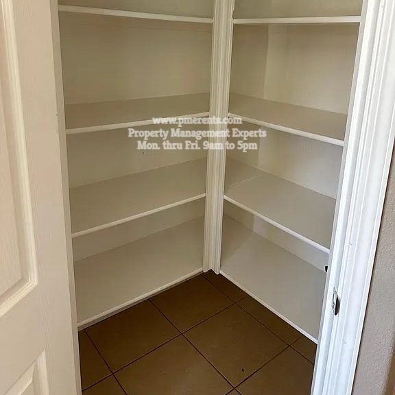 a white pantry with shelves and a door.