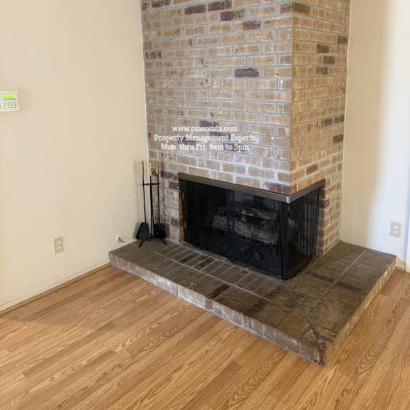 a brick fireplace in a room with wooden flooring.