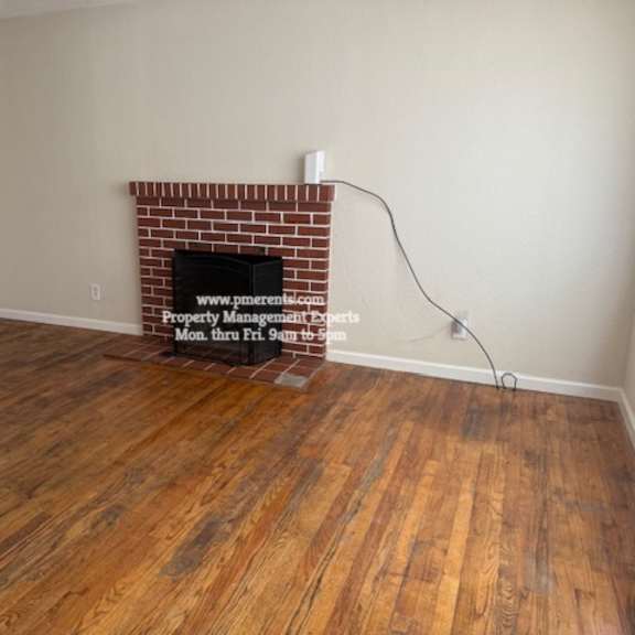 a room with a brick fireplace and wooden floors.