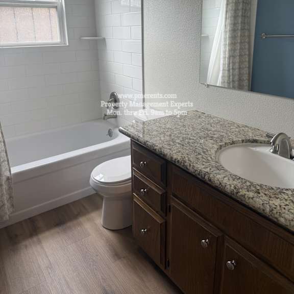 a bathroom with a white toilet, a bathtub, and a sink.