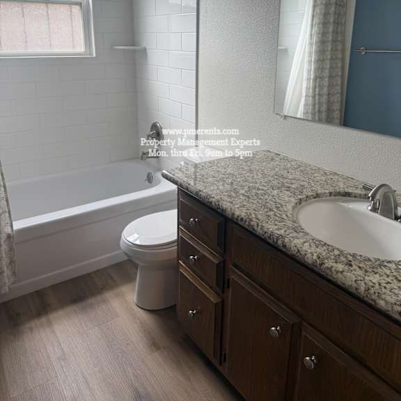 a bathroom with a white toilet, a bathtub, a sink, and a mirror.