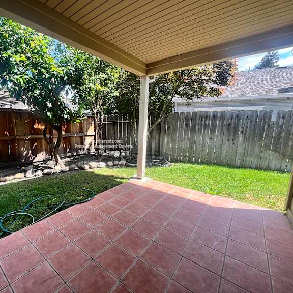 a patio with a hose and a fence.