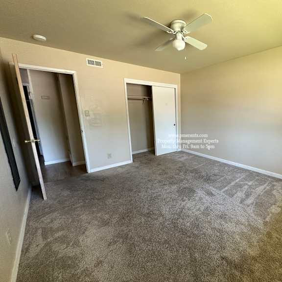 a room with a ceiling fan and carpeted floor.