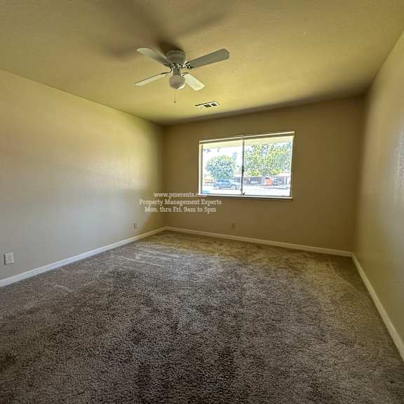 a room with a carpeted floor and a ceiling fan.