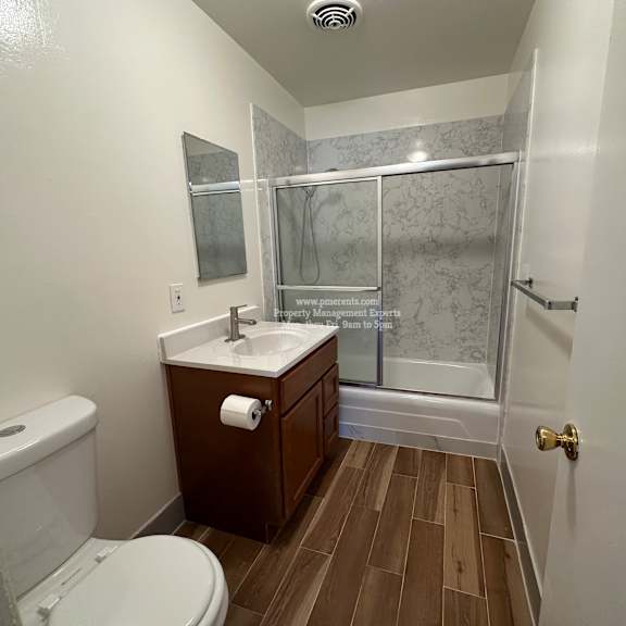 a bathroom with a toilet, sink, and shower.