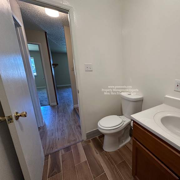 a bathroom with a toilet, sink, and mirror.