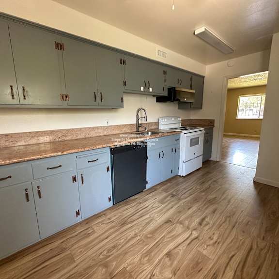 a kitchen with white cabinets and a wooden floor.