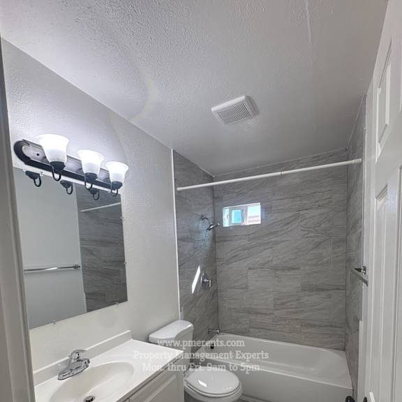 a bathroom with a white sink, toilet, and a bathtub.