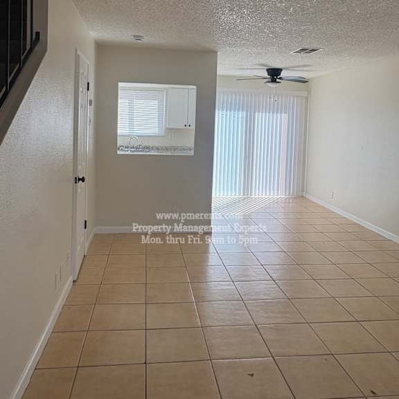 a room with a fan and a window with blinds.
