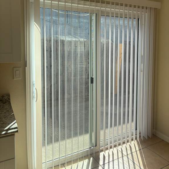 a sliding glass door with white blinds partially closed.