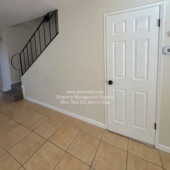 a white door is in a room with a staircase.
