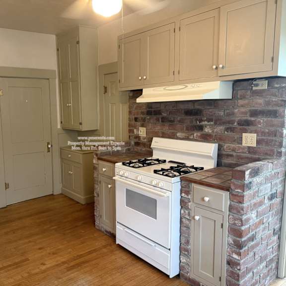 a kitchen with a white stove and a brick wall.
