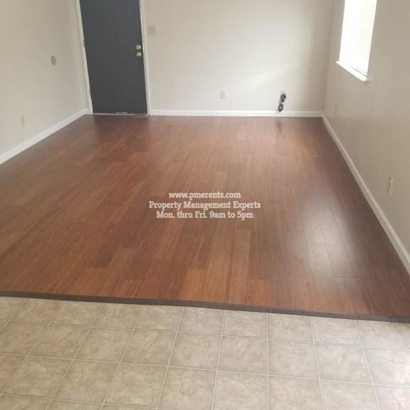 a room with wooden flooring and a black door.