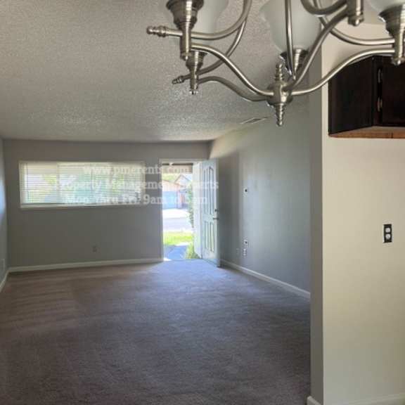 a room with a carpeted floor and a chandelier hanging from the ceiling.