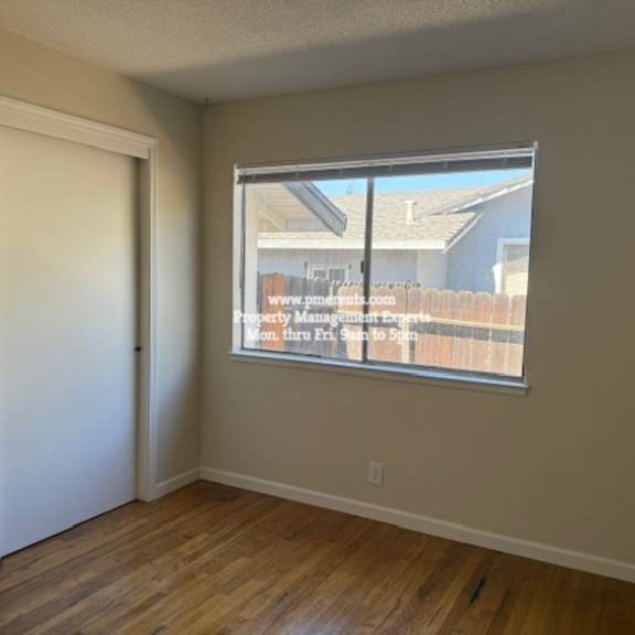a room with a window showing a view of a house and a fence.