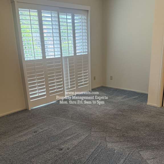 a room with a carpeted floor and a window with blinds.