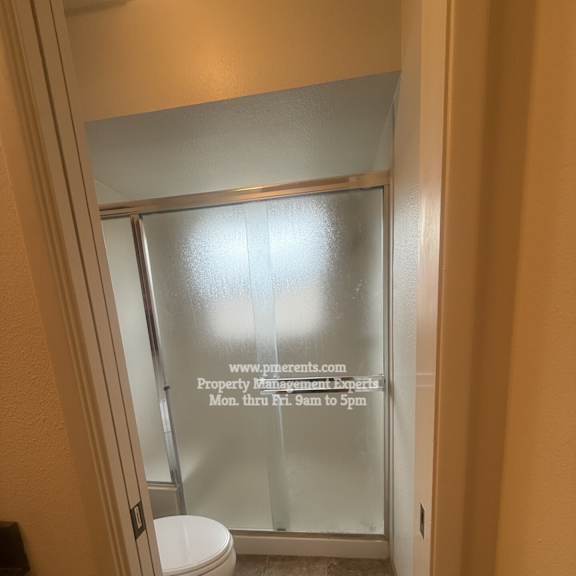 a bathroom with a toilet and a glass door.